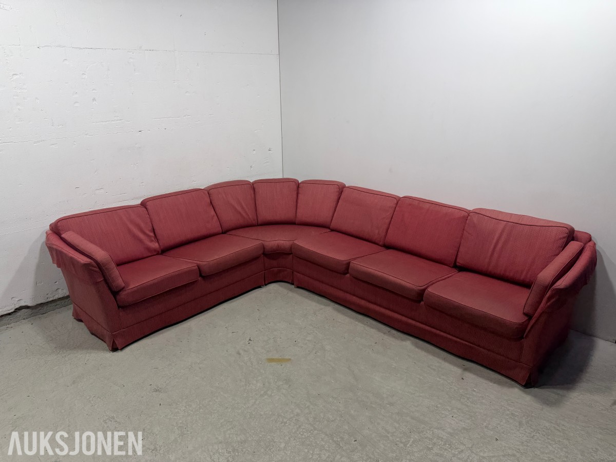 Stor rød hjørnesofa med rundt salongbord