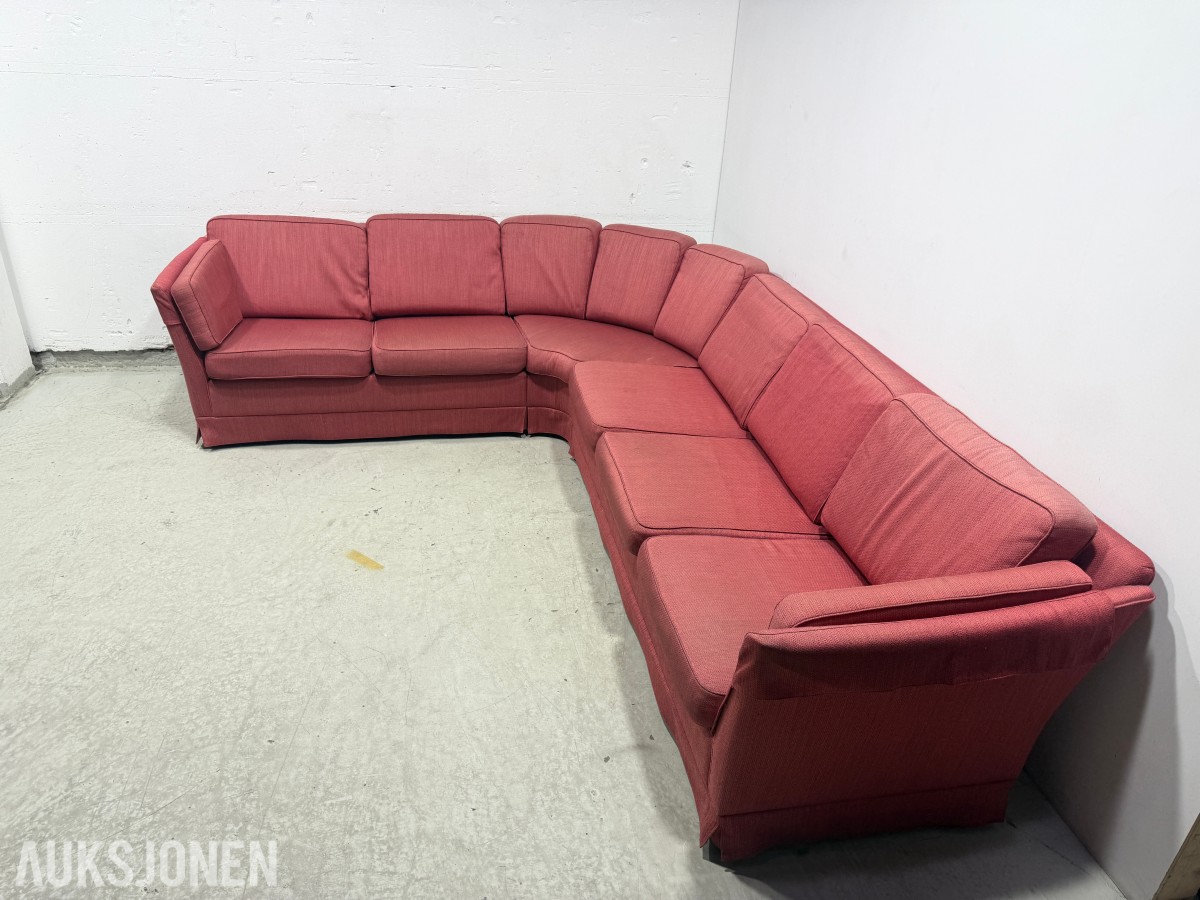 Stor rød hjørnesofa med rundt salongbord