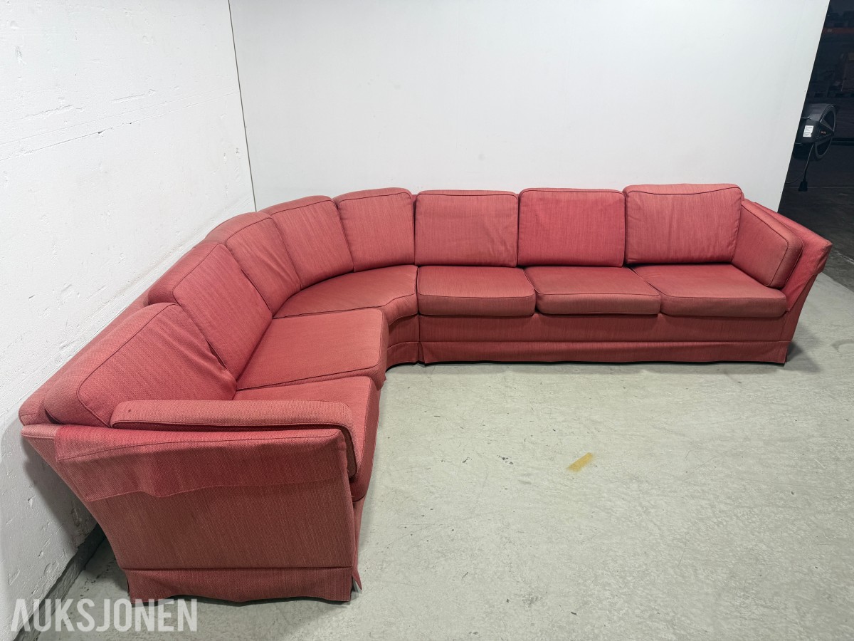Stor rød hjørnesofa med rundt salongbord